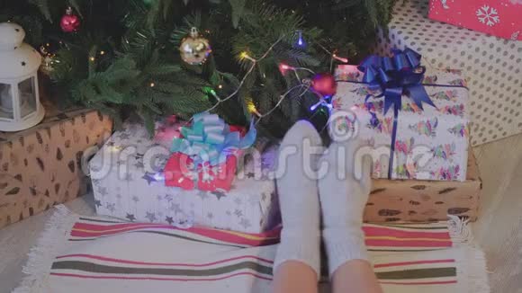 特写镜头女人脚穿着圣诞袜靠近圣诞树假日女人脚踩圣诞树和礼物视频的预览图