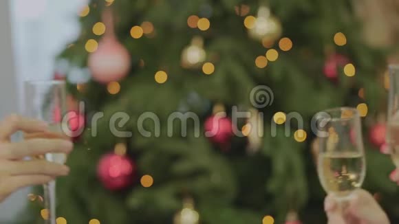 圣诞新年在圣诞树的背景上祝酒朋友们在背景上碰杯香槟视频的预览图