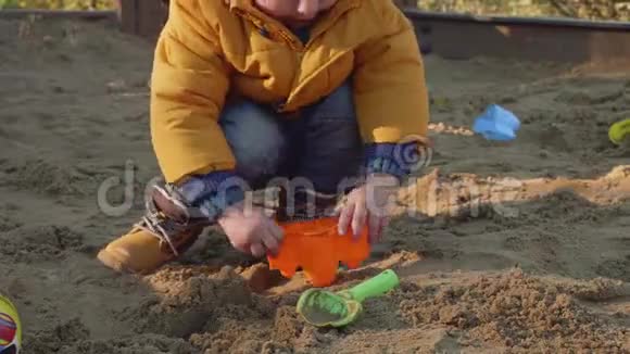 白人金发小孩在沙坑里玩玩具车视频的预览图