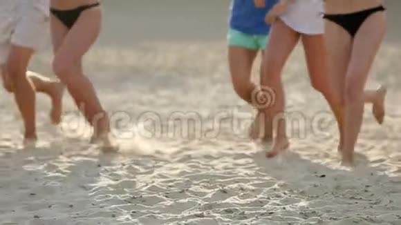 日落时一群朋友的腿跑进海水中在海滩上扔衬衫快乐快乐视频的预览图