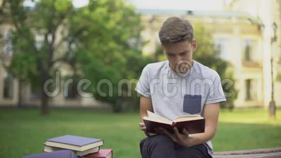 集中青少年在长凳上的公园看书准备考试视频的预览图