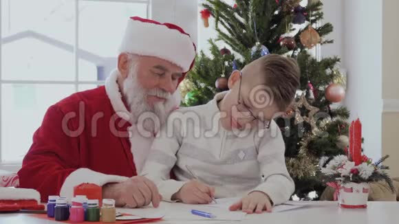 男孩坐在圣诞老人的腿上用平底锅画画视频的预览图