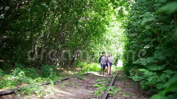 阳光明媚的日子快乐的少年们在森林里废弃的铁路上奔跑视频的预览图