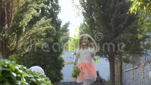 可爱的小女孩穿着粉红色的裙子在花园的绿树丛中奔跑视频的预览图
