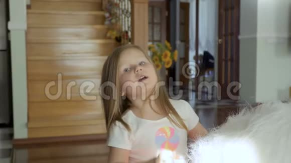可爱的小女孩坐在柔软的玩具上抚摸她的头发视频的预览图