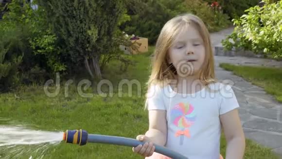 小女孩用水管给花坛浇水视频的预览图