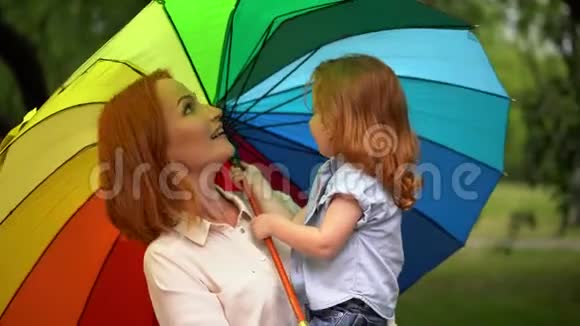 在彩色雨伞下快乐的妈妈和女儿视频的预览图
