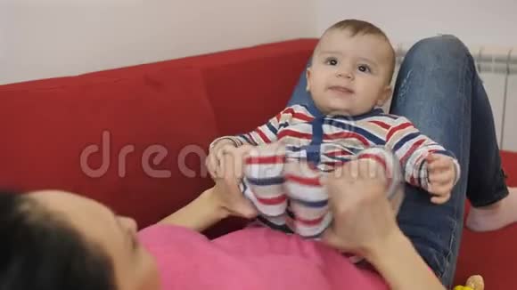 母亲坐在沙发上腿上微笑婴儿的画像视频的预览图