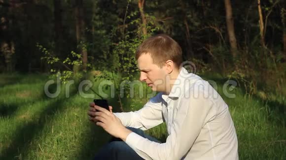 一个手里拿着一瓶啤酒在大自然里打电话的人视频的预览图