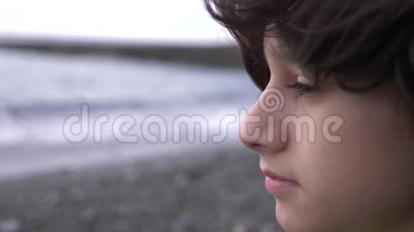 一个可爱的少年卷发在大海的背景下4k慢动作视频的预览图