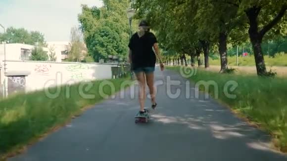 女孩在夏天的公园里在街上骑滑板视频的预览图