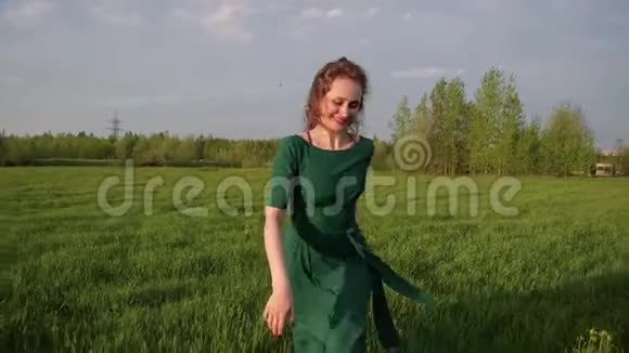 年轻快乐的美丽女子穿着一件连衣裙沿着绿色的田野奔跑视频的预览图