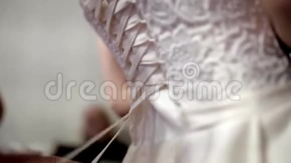 妈妈帮新娘穿上婚纱库存双手系一件婚纱视频的预览图