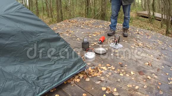 旅行者站在帐篷附近以室外的木地板和杯子里的沸水为基础他泡茶不可见视频的预览图