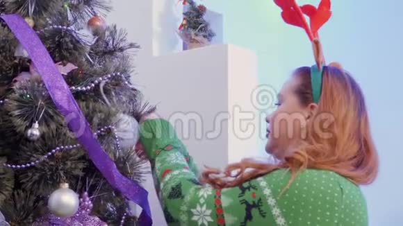 头上长着鹿角的漂亮胖女孩装饰圣诞树视频的预览图