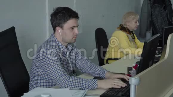 带着耳机的年轻人在办公室的电脑里工作视频的预览图