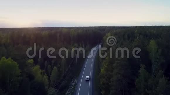 地平线上的光明天空和黑暗的森林路上有车视频的预览图
