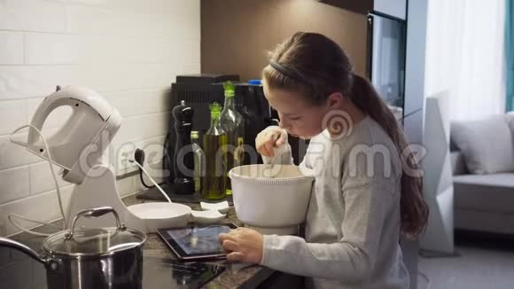小女孩在厨房里用平板电脑做食物视频的预览图