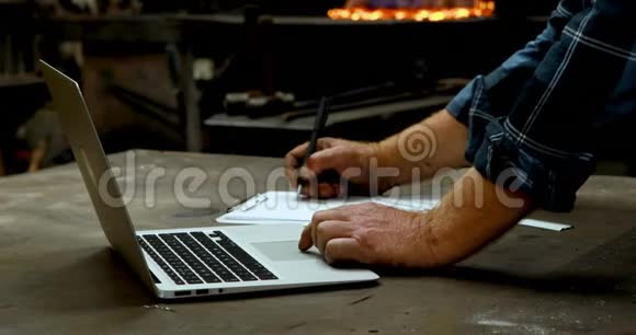 铁匠在4k车间使用笔记本电脑时在剪贴板上写字视频的预览图