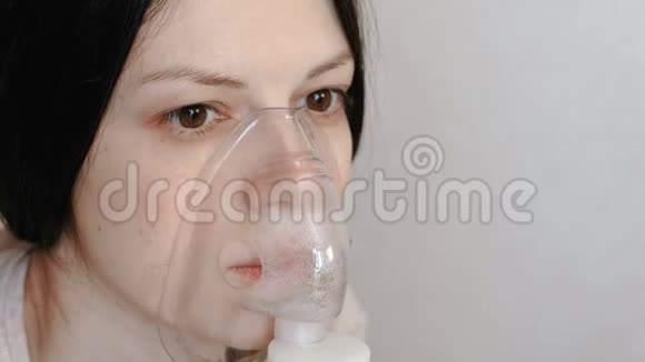 使用雾化器和吸入器进行治疗特写女人她的脸通过吸入面罩吸入正面观点视频的预览图
