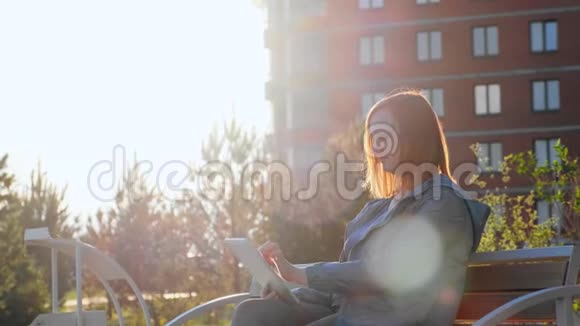 坐在城市长凳上用平板电脑的女人视频的预览图
