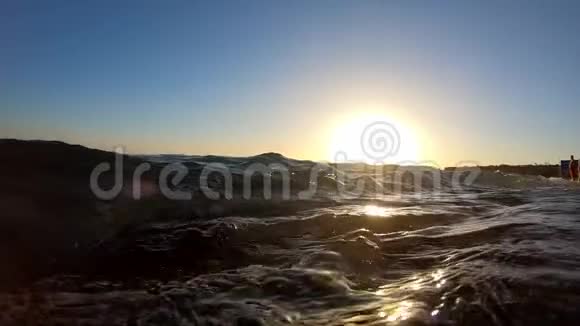 当波浪在日落时缓慢移动时照相机潜入水中视频的预览图