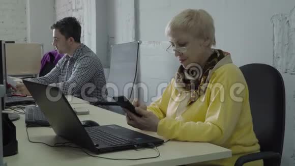 退休妇女在工作期间在办公室使用电话视频的预览图