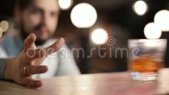 酒吧里的人在喝威士忌特写镜头把玻璃滑过吧台打在手上视频的预览图