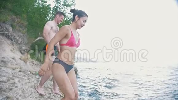 一个女孩和一个男人在水中跳跃在大自然中度假慢动作视频的预览图