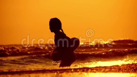 日落时分快乐的女孩在海滩上玩耍日落时在浅水中奔跑的女孩孩子在水里玩视频的预览图