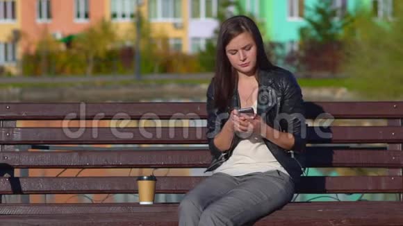 公园里一个年轻迷人的女孩坐在长凳上在打电话视频的预览图