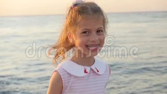 美丽的小女孩在海洋的背景下又笑又跳视频的预览图
