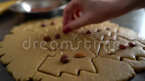 女人手工装饰的原始饼干以圣诞树的形式坚果特写视频的预览图