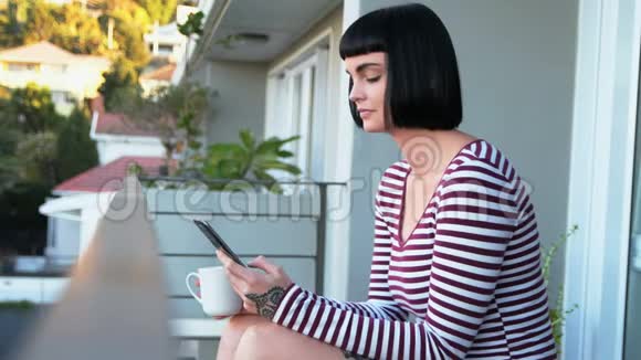 在阳台上用手机喝咖啡的女人视频的预览图
