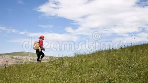 女孩摄影师在高原悬崖和云层的背景下上山概念视频的预览图