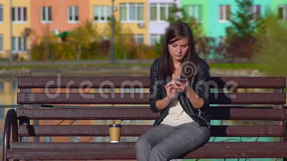 公园里一个年轻迷人的女孩坐在长凳上在打电话视频的预览图