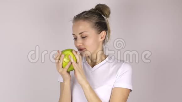 漂亮的年轻女孩咬了一个大绿苹果她抬起拇指微笑着视频的预览图