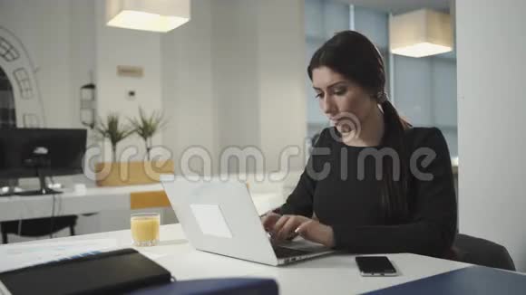一个在电脑前工作喝橙汁的女人视频的预览图