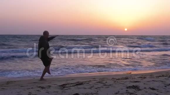 男子训练太极拳在傍晚海边日落时在户外训练视频的预览图