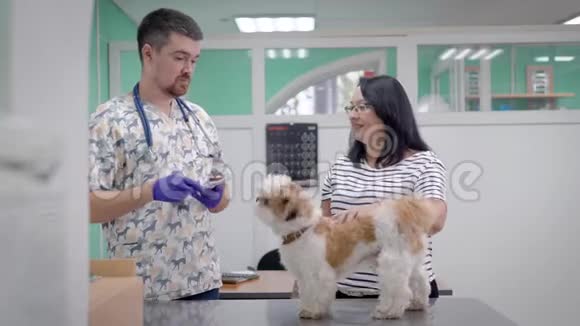 穿着兽医制服的男人和带狗的女人说话视频的预览图