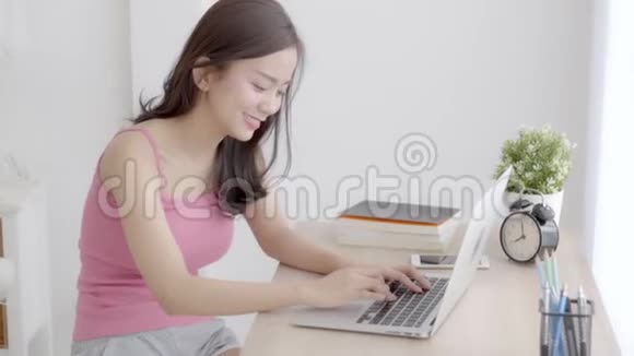 美丽写真亚洲女青年微笑工作在线笔记本电脑开心满意坐在办公桌上视频的预览图