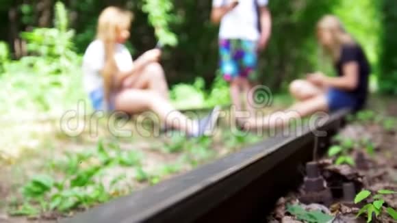 三个青少年朋友把智能手机挂在森林废弃的铁路上视频的预览图