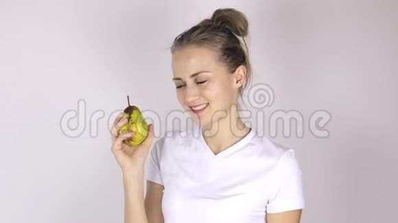 美丽的年轻女人咬多汁的梨视频的预览图