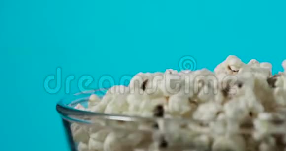 蓝色背景上带有新鲜爆米花的旋转玻璃碗的一部分视频的预览图