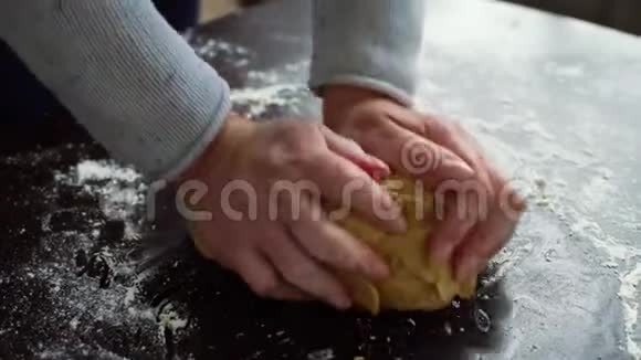 女人的双手将生面团捏在满是面粉的桌子上视频的预览图
