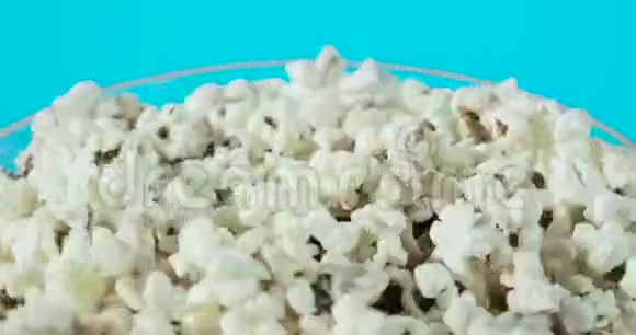 蓝色背景上带有新鲜爆米花的旋转玻璃碗的一部分视频的预览图