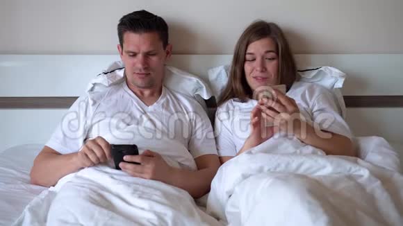 配偶躺在床上看智能手机视频的预览图