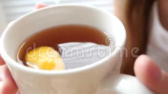 热的金茶和柠檬片女孩在她的手中站在窗口视频的预览图