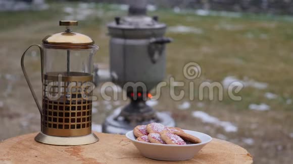 在寒冷的季节在后院的一个杯子里倒茶大的旧萨莫瓦尔4K视频的预览图