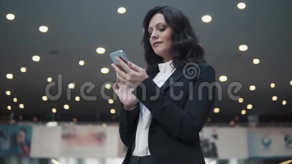 一位身着商务套装的妇女走过一座现代化办公楼的大厅女商人用手机视频的预览图